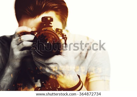 Sunset shot. Digitally composed close-up picture of young photographer looking threw his camera over the picture of landscape with palm trees