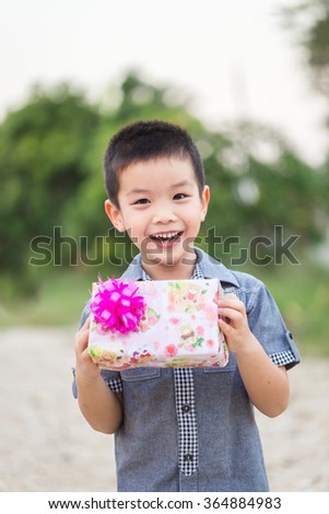Asian child holding Christmas gift box in hand with smiling face