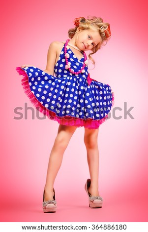 Pretty little girl in her mother's shoes and hair curlers. Kid's fashion, cosmetics. Pin-up style.