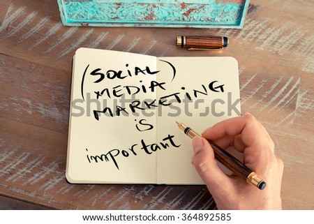 Retro effect and toned image of a woman hand writing a note with a fountain pen on a notebook. Handwritten text SOCIAL MEDIA MARKETING IS IMPORTANT, business success concept