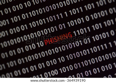 'Phishing' word in the middle of the computer screen surrounded by numbers zero and one. Image is taken in a small angle.
