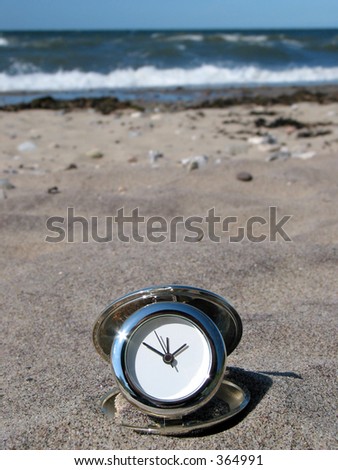 Chrome clock lying on the beach