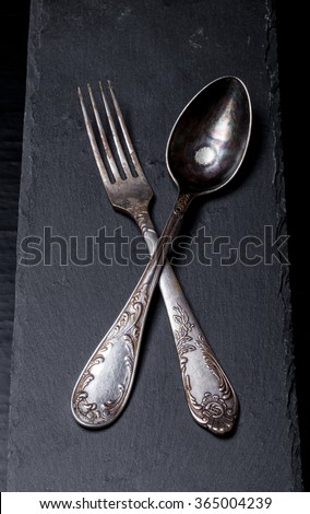 Fork and spoon on a plate of slate on a black background.