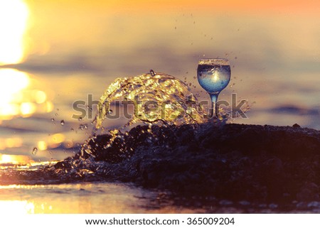Glass of white vine with reflections of sun and sea on the background of beautiful sunset. Selective focus. Toned.
