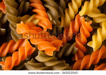 Various mix of pasta on wooden rustic background, sack and wooden spoons. Diet and food concept. Colored natural pasta. Spinach, beetroot, egg