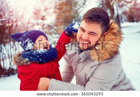 active father and son playing snowballs in winter park