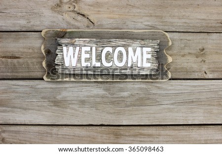 Rustic wood welcome sign hanging on old weathered wooded background