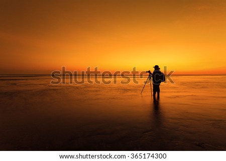Silhouette  of Male photographer taking picture  on the beach at sunset time
