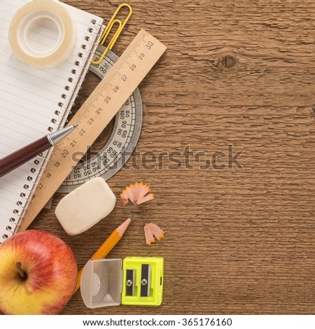 School supplies and apple on wooden background 


