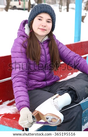 teen beautiful girl with long dark hair put on ice skate boots before skating on the ice outdoor skate rink