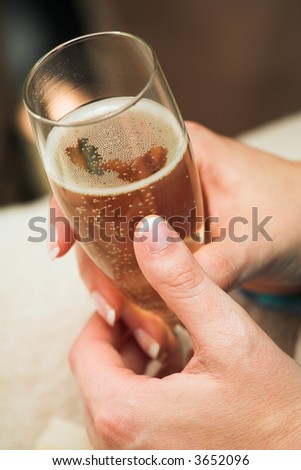 Young woman holding a glass champagne flute (shallow Depth of Field – focus on bubbles)