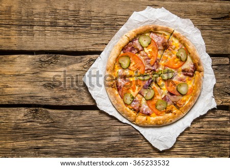 Fresh tasty pizza with tomatoes and ham.  On wooden background. Top view