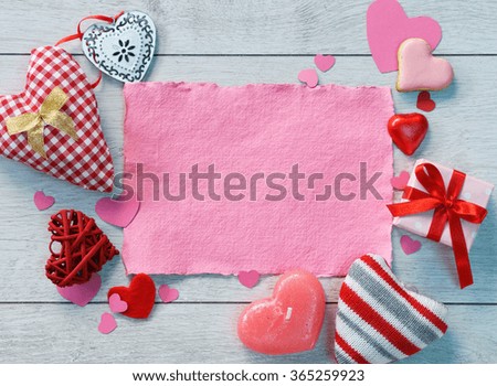 Pink paper among hearts on a wooden background. Valentines Day concept