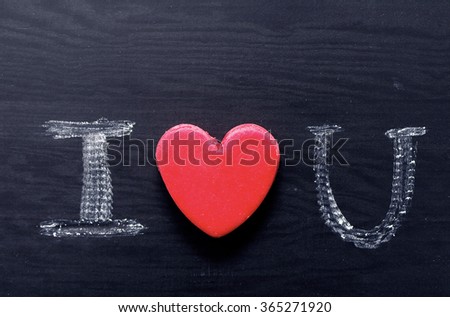 Text "I love you", written by chalk on a black board. Romantic card St. Valentine's Day. Red heart and declaration of love