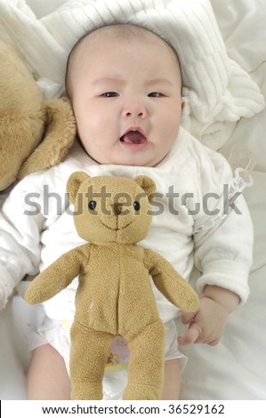 baby girl lying in bed with her teddy bear