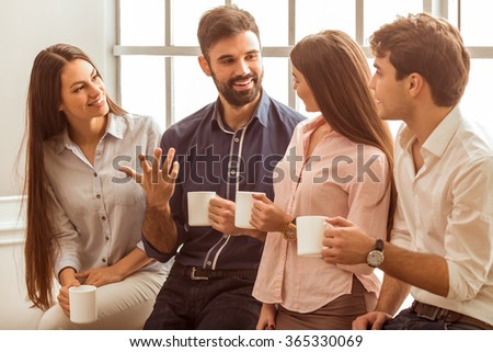 Coffee break chat. Group of attractive business people, standing next to each other, holding a cups, smiling standing at the window Royalty-Free Stock Photo #365330069