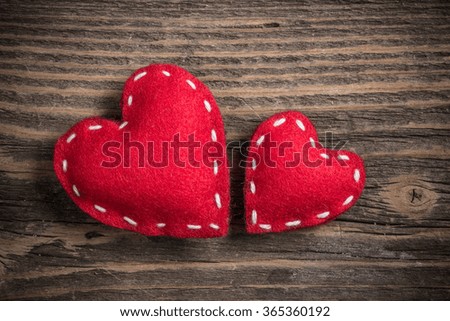 Two red felt hearts on old wooden background 