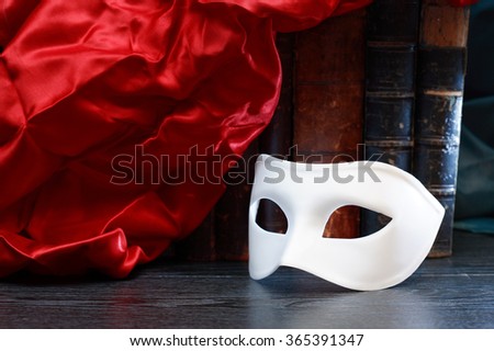 Theater concept. Closeup of white classical carnival mask on books background