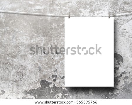 Close-up of one hanged paper sheet with pegs on stained scratched concrete wall background