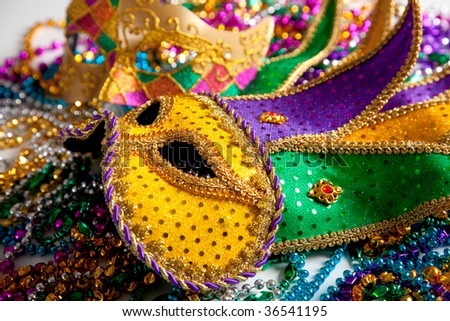 A group of two mardi gras mask and beads