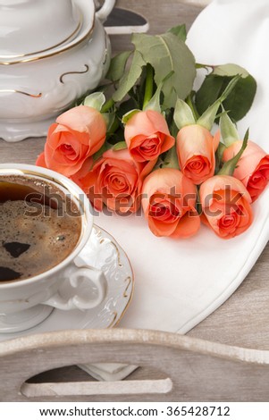cup of coffee and a bouquet of roses on a tray