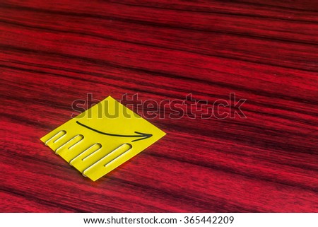 Paper clips attached by size on a yellow note with an arrow written on it.