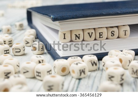 Invest word written on wood block. Wooden ABC.