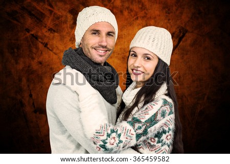 Smiling couple hugging and looking at camera against shades of brown