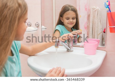 Girl closes after washing the mixer tap in the bathroom Royalty-Free Stock Photo #365468339