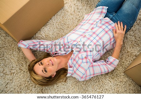 Woman lying on her carpet next to boxes
