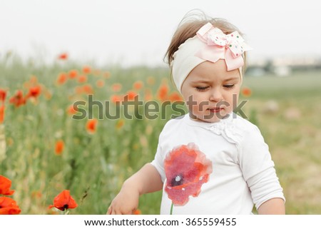 Closeup of a cute girl in poppy field of flowers in the open air. The girl in the poppies. Happy kid with poppies.