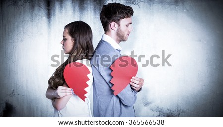 Side view of young couple holding broken heart against grey background