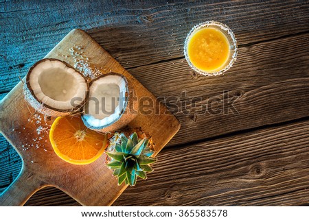 fruit pineapple smooties with coconut and orange on wooden table, picture with blue light and postprocess 