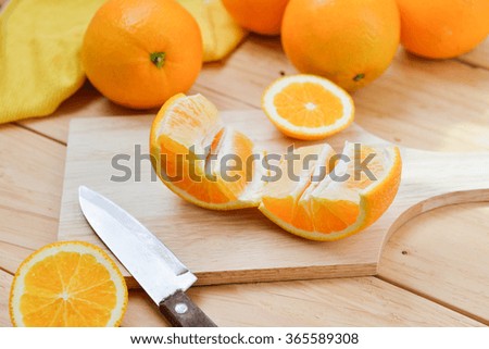 Fresh and juicy half and slice of orange fruit on a chopping block on weathered wooden table background.