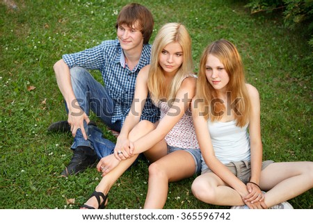 Three teenagers sit on the grass.High angle view