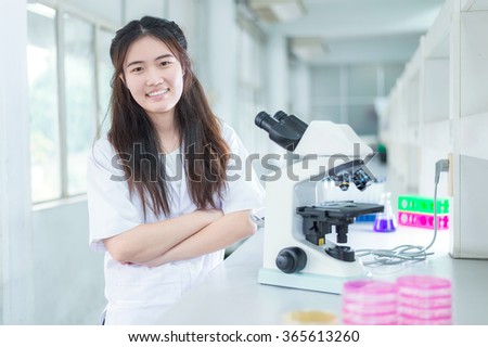 Cute scientist cross one's arm and smiling in laboratory room.
