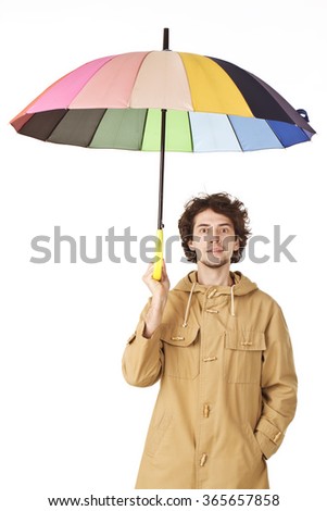 Handsome man in light brown vintage raincoat holding colorful umbrella.
