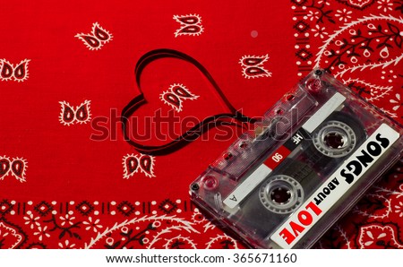Valentines day card - audio, cassette with magnetic tape in shape of heart on cowboy red background .