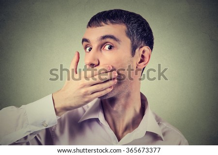 Headshot of a scared adult man with hand covering his mouth isolated on gray wall background  
