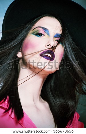 beautiful young woman with colorful makeup and hat portrait in studio