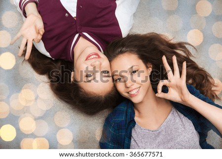 happy smiling pretty teenage girls lying on floor