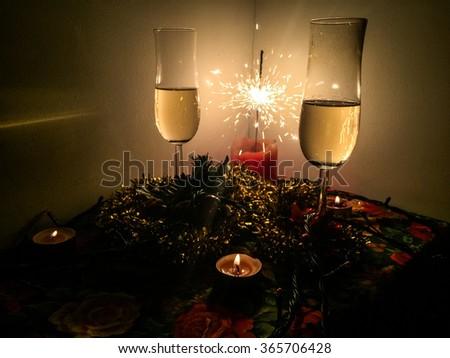 Picture of champagne glasses on Christmas lit up by candles. light garlands and sparklers