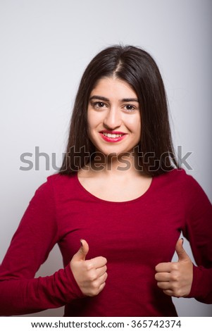 brunette business woman happy showing a thumb up, everything is OK, in a red dress, studio isolated portrait emotions
