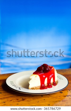 Strawberry Cheesecake with syrup close up in white dish on wooden table background , Strawberry Jam , New York Cheesecake , Delicious homemade cheesecake with strawberries on white wooden table.