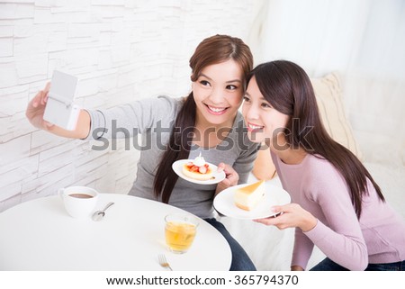 Two happy young female friends take selfie picture by smart phone, with coffee cups and cakes in the living room at home, healthy lifestyle concept, asian beauty