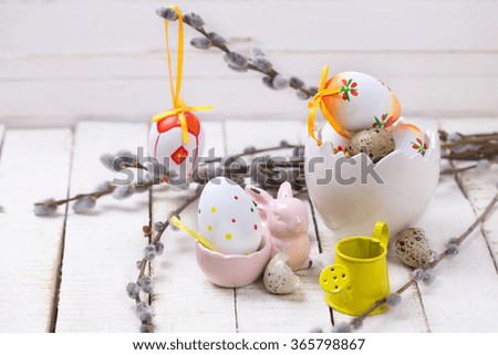 Decorative Easter eggs in bucket, willow  branches  and rabbit on wooden background. Easter background.