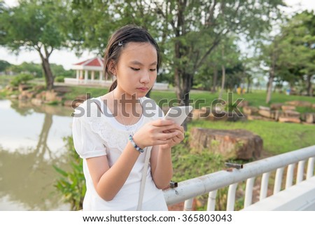 Asian teen playing smartphone in playground