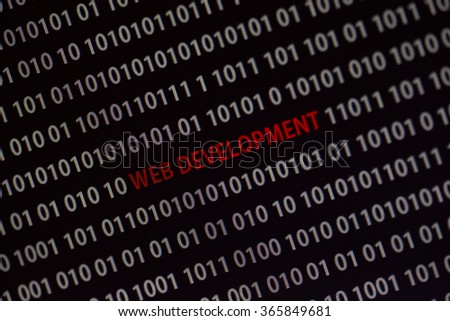 'Web development' text in the middle of the computer screen surrounded by numbers zero and one. Image is taken in a small angle.