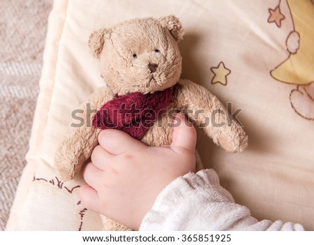 five months old  sweet baby sleeping on a blanket with a bear