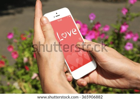 Female hands holding smart mobile phone with romantic screensaver outdoors